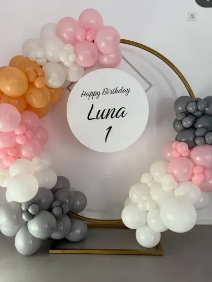 A simple and modern balloon ring in grey, white, pink, and orange for a first birthday.