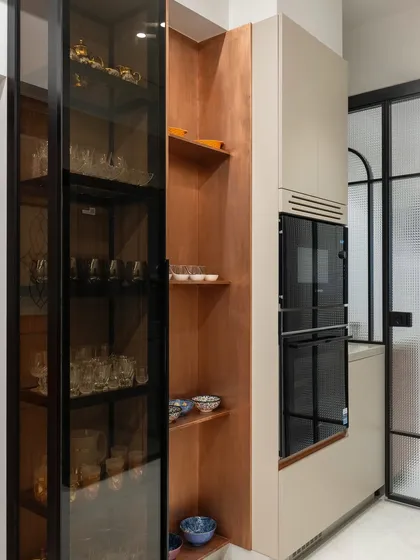 We turned an otherwise wasted column into a beautiful and functional storage unit. The narrow-depth cabinets and glass-fronted crockery unit are finished in wood, while the adjacent open shelves are clad in copper for a warm, soft touch.