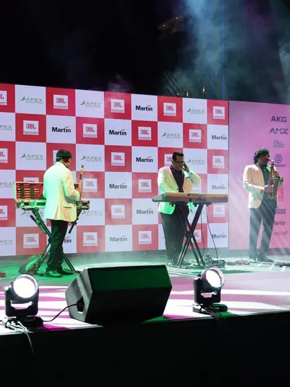 A close-up of the band performing on stage, showcasing the clarity of the LED backdrop and the professional stage monitoring setup. Every detail is managed to ensure a high-quality production.