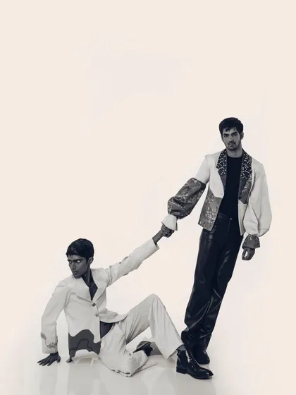 A black and white version of a shot from the "Monsieur" editorial. Stripping away the color highlights the textures and forms of the garments, from the printed sleeves to the sleek leather pants.