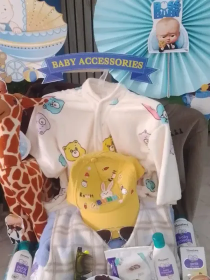 A cart filled with baby accessories, including a soft giraffe toy, baby powder, and warm clothing.