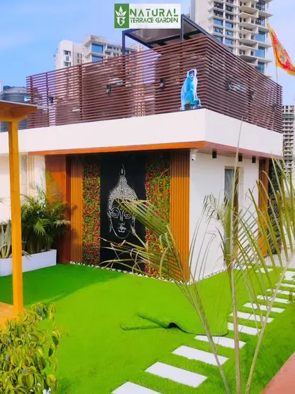 A daytime view of a completed project in Gwal Pahari, Gurgaon, showing the clean lines of the design, with a white-walled structure and lush green lawn.