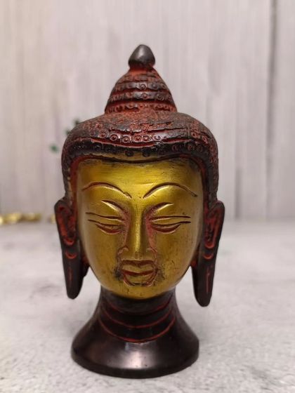 A multi-color brass Buddha head with red and black accents, offering a more artistic and decorative take on the symbol of peace.