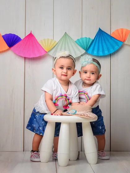 Two little twins ready for an adventure. This colorful setup with a rustic wood background captures the playful side of their twinship.