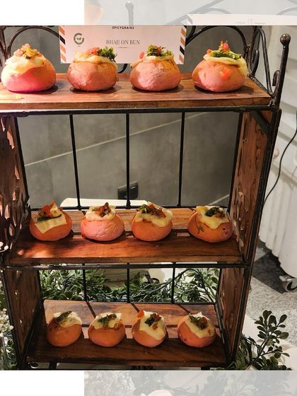 Bite sized Pav Bhaji served in pink buns, displayed on a rustic wooden stand. This creative twist on a beloved classic adds a pop of color and fun to any event menu.