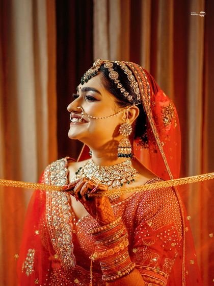 A lovely portrait of the bride, her face illuminated by warm light. She holds her veil, creating a traditional and graceful pose.
