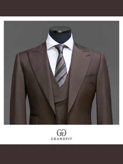 A detailed view of a rich brown three-piece suit, focusing on the peak lapels and the coordinated waistcoat. This color offers a warm and distinguished option for business wear.
