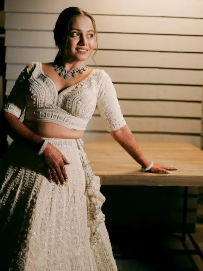 A close-up portrait highlighting the soft, glowing makeup that complements the white lehenga.