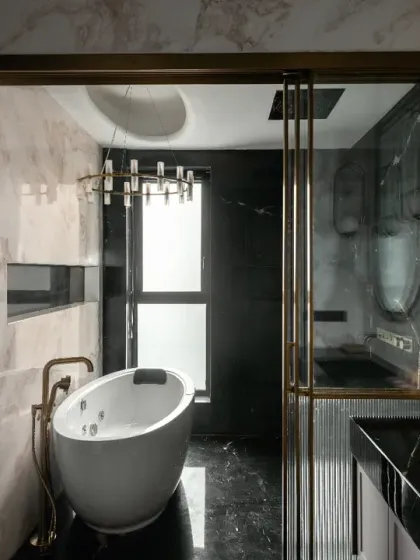 This bathroom in the House of Dancing Screens is a study in modern glamour. The freestanding bathtub, dramatic chandelier, and interplay of black marble and brass detailing create a personal spa that is both luxurious and deeply personal.