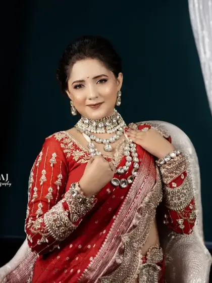 A classic seated bridal portrait. The bride looks elegant and poised in her red and silver lehenga against a shimmering backdrop.