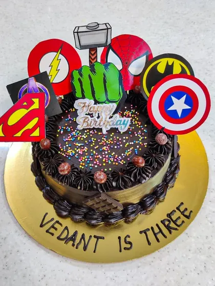 When you can't pick just one hero, you assemble them all. This Avengers-themed cake is topped with logos from multiple heroes like Captain America, Batman, and The Hulk, perfect for a third birthday party.