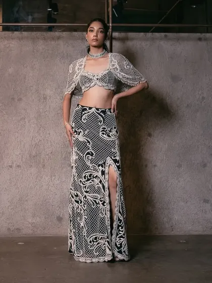 A chic monochrome ensemble featuring a pearl-embellished crop top and a straight skirt with a high slit, perfect for any occasion.