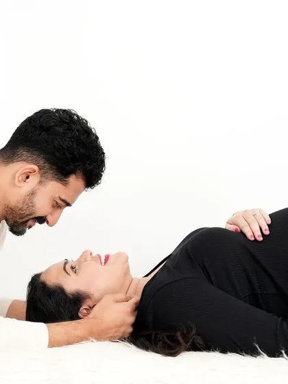A tender and intimate moment with a couple lying on a white rug. The simple black and white outfits keep the focus entirely on their connection and loving expressions.