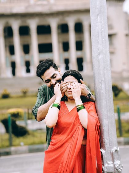 A playful 'guess who' moment on a city street, with the Vidhana Soudha in the background, blending fun and iconic Bangalore scenery.