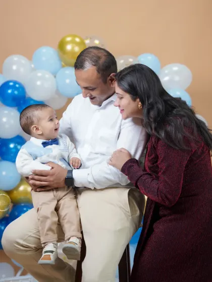 Capturing the playful interactions that make your family unique. This candid shot from a first birthday session shows the genuine smiles and love shared between parents and their child.