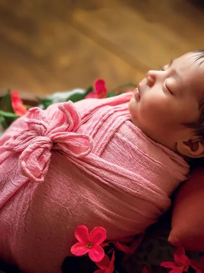 A beautiful overhead shot of a baby wrapped in pink and surrounded by flowers. Using props like this basket allows for creative angles and compositions.
