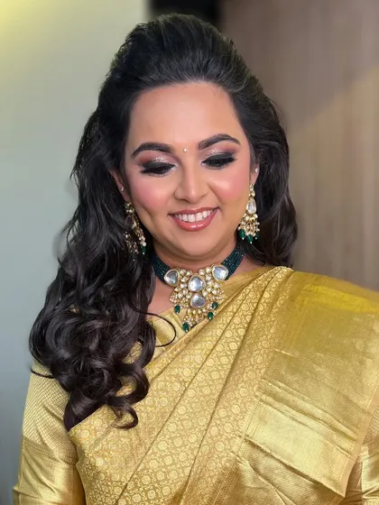 A stunning engagement bride in a traditional golden saree. Her makeup features a classic smokey eye and a radiant smile.