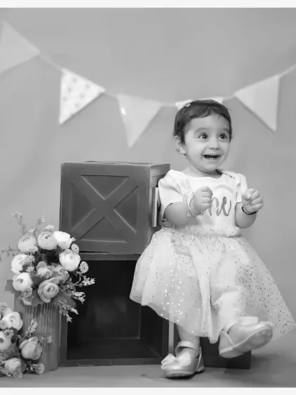A joyful black and white portrait from a first birthday shoot. The genuine smile and simple props create a timeless and heartwarming memory.