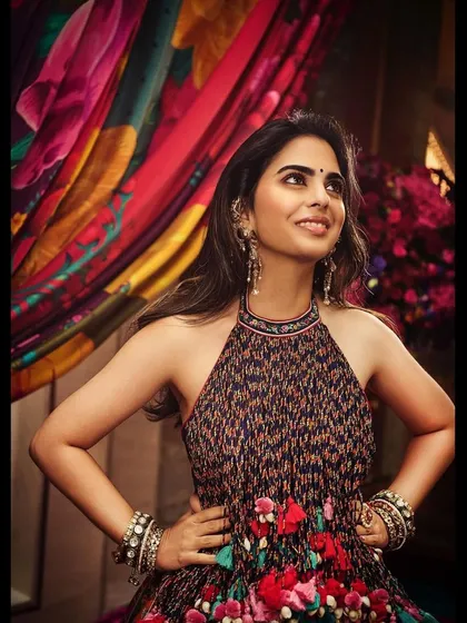 Isha looking radiant against a colorful backdrop that complements her vibrant Torani lehenga. This shows how we consider the entire visual frame during a shoot.