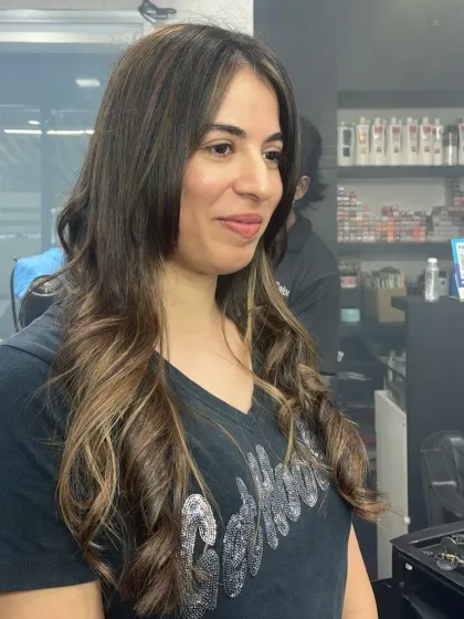 A beautiful shot of a client's new hairstyle, featuring soft, natural-looking waves and highlights that catch the light perfectly.