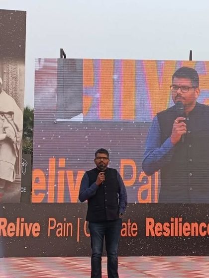 On stage at Central Park, New Delhi. The screen behind me amplifies the message: Relive Pain, Celebrate Resilience, Reclaim.