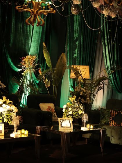 A lounge corner from the 'Jungle Disco' sangeet, where emerald green drapes, tropical foliage, and custom zodiac-themed cushions came together. The lighting was kept moody to enhance the feeling of being in an enchanted forest.
