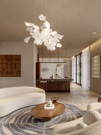 This perspective of the Siroi Lilly living room highlights the open, airy feel. The design connects the seating area to a bar and dining space in the background, all unified by a consistent material palette and a stunning feature chandelier.