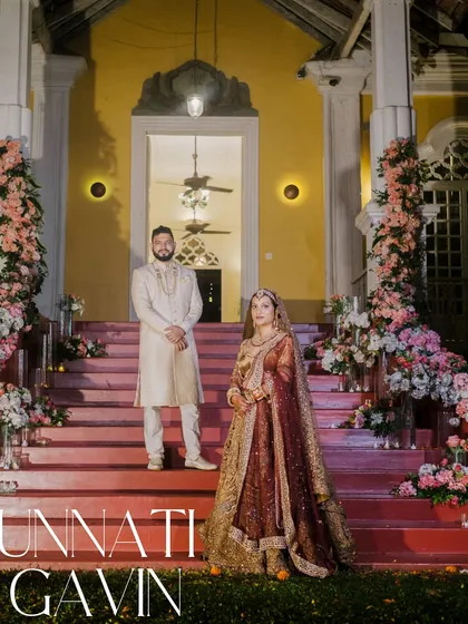 A regal portrait of the couple on the grand staircase of their Goa wedding venue, the Silva Heritage, showcasing the charm of a heritage property wedding.