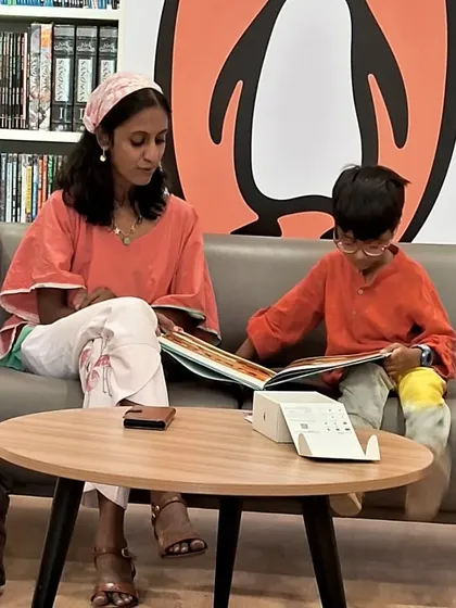 A mother and son reading together on our comfy couch. We've created cozy nooks throughout the store for shared reading experiences.