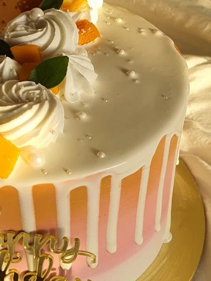 A close-up shot of the white chocolate drip and fresh mango topping on this birthday cake. The little pearl sprinkles add a touch of elegance.