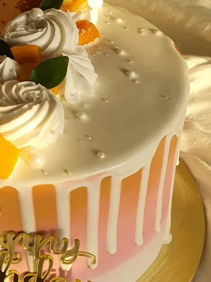 A close-up shot of the white chocolate drip and fresh mango topping on this birthday cake. The little pearl sprinkles add a touch of elegance.