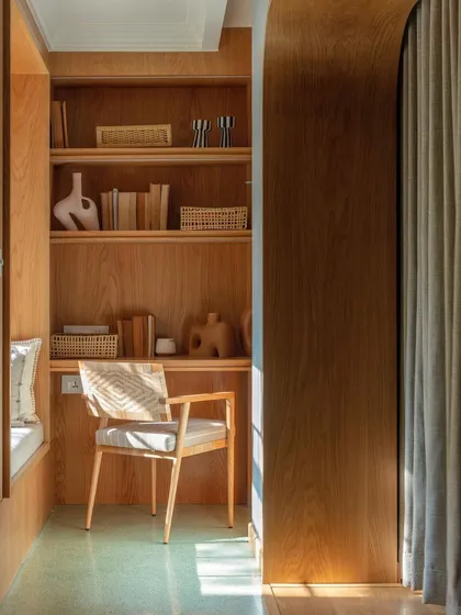 A cozy study nook carved out in the 'Summer Haus' kids' suite. The space is fully clad in warm wood, creating a built-in feel with integrated shelving and a window seat, perfect for reading and homework.