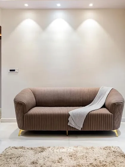 A set of plush, brown-toned sofas arranged in a formal living room. The soft lighting and simple decor create an elegant and comfortable space for conversation and relaxation.