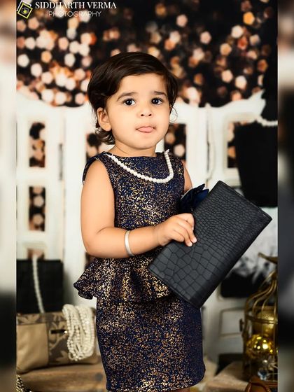This little girl strikes a pose with a clutch purse, looking like a natural model in her stylish outfit.