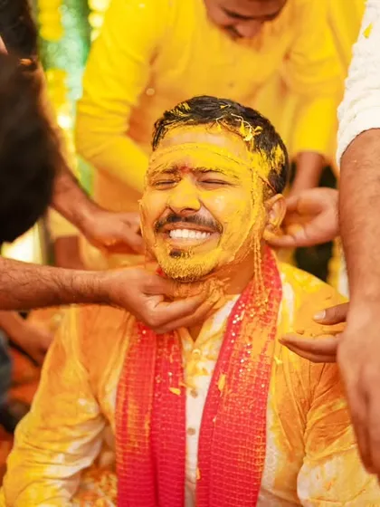 The groom gets his share of the Haldi fun, a candid moment of laughter and celebration with his friends.