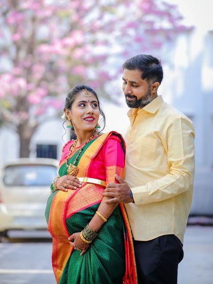A lovely couple portrait taken outdoors during a maternity session. The focus is on their happy interaction, with the mother-to-be looking up at her partner.