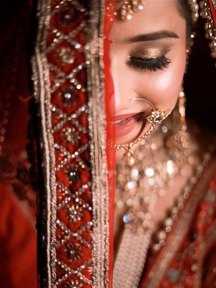 A playful and shy peek from behind the dupatta. This candid moment shows the bride's joy and the beauty of her makeup.