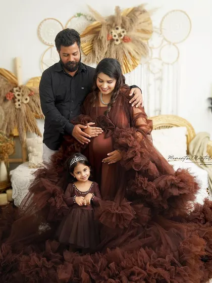 A beautiful family of three, soon to be four. The matching brown outfits and the daughter's tiara make this a truly special family portrait.