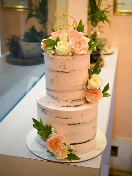 The simplicity of a semi-naked cake is just beautiful. This two-tier engagement cake for a dear friend features lightly frosted layers, allowing the cake to peek through, and is decorated with fresh peach roses and greenery.