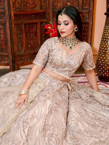 This beige and silver embroidered lehenga is subtle yet stunning. It's paired with an emerald green necklace to add a touch of colour.