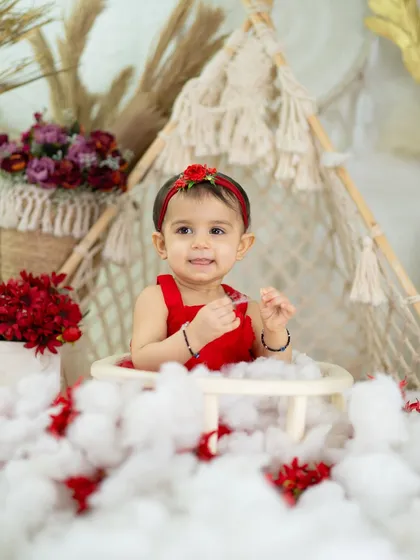 A happy smile that shows the beauty of simplicity. The red outfit pops against the neutral, textured backdrop.