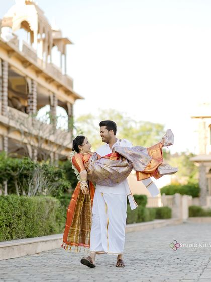 A joyful and romantic moment as the groom lifts his bride in front of a stunning palace in Pushkar. Her traditional saree and his classic white outfit look beautiful against the heritage backdrop.