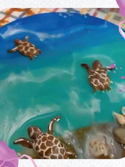 A stunning close-up of a finished resin art piece. You can see the layers of color that create the ocean effect and the carefully placed turtles swimming in the sea.