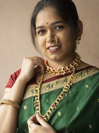 This is a simple yet elegant Maharashtrian look, featuring a choker and matching long necklace with red and green stones, perfect for a family function.