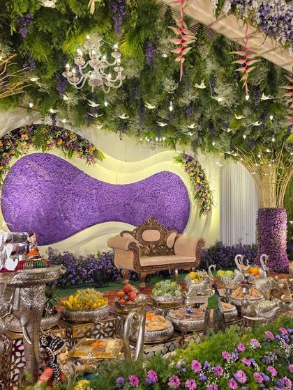 A close-up view of the offering table in front of the purple floral stage, showing the silver elephant and swan props.