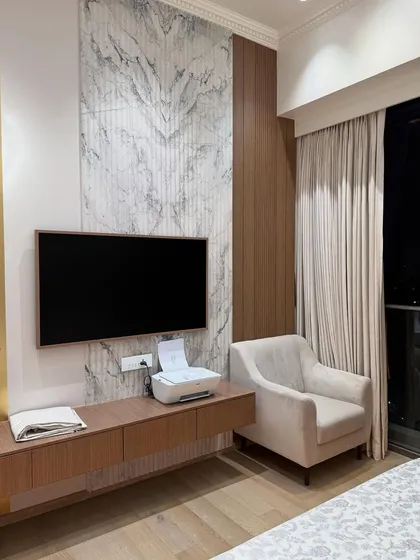 A bedroom TV unit design that combines a marble-finish panel with wooden fluting. This setup provides a dedicated space for entertainment without compromising on style.