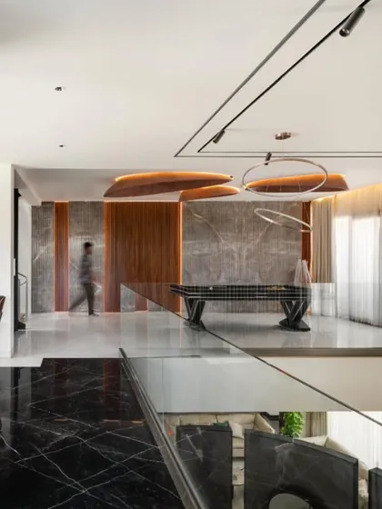 This space features a concealed master bedroom entry behind a wall of fluted teak. The bold-veined marble floor and elliptical ceiling forms create a sense of drama and fluidity, showcasing our attention to material and form.