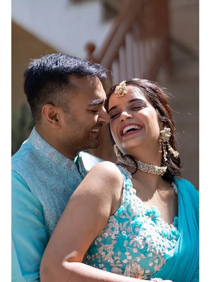 A candid shot of the couple sharing a laugh during their Mehendi function, showcasing their relaxed and happy connection.