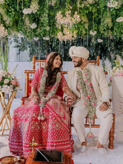 A beautiful couple on their wedding stage. The bride's soft curls look beautiful with her pink lehenga and the floral decor.