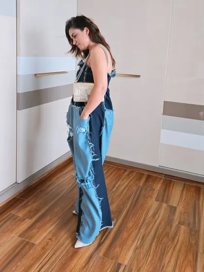 Another look at the deconstructed denim jumpsuit, this time showing how it looks with a small, elegant crossbody bag. This demonstrates how to balance an edgy outfit with more refined accessories.